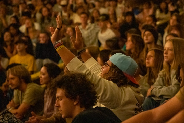 Students with hands raised during indoor worship at Hume.